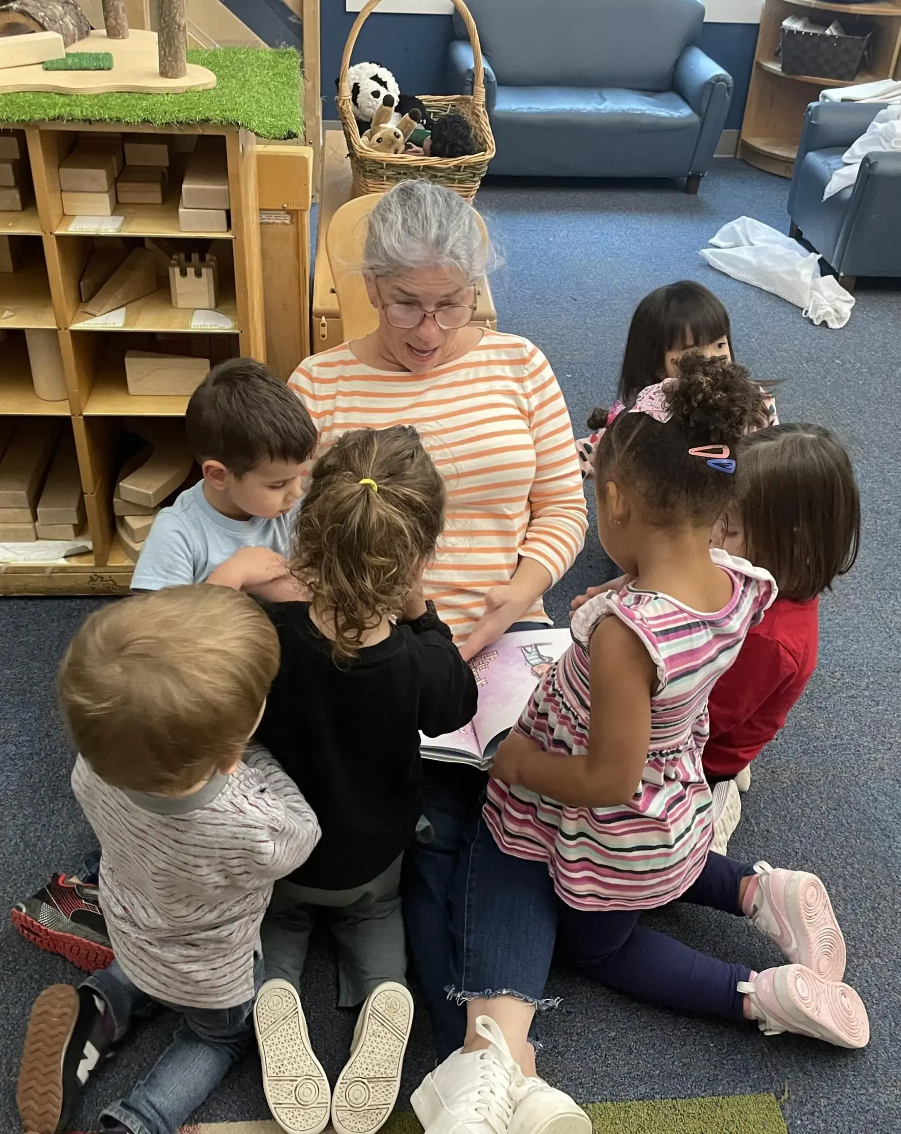 A Bigelow teacher reading to a group of preschoolers seated on the classroom floor