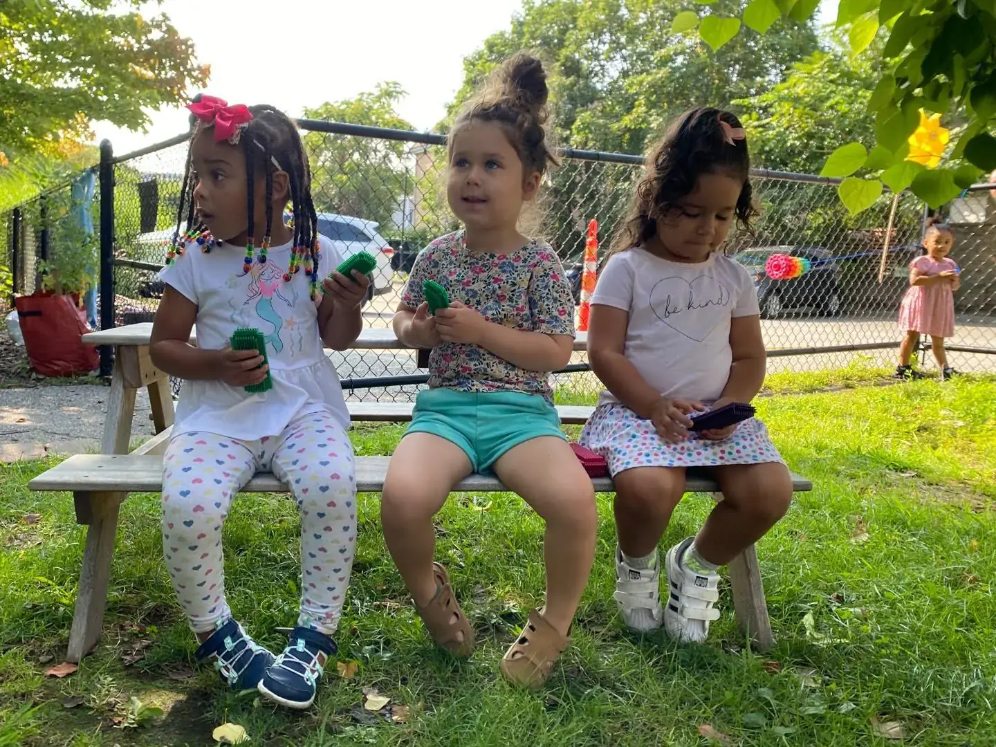 Three children sitting together on a bench in the Bigelow playground on a summer day