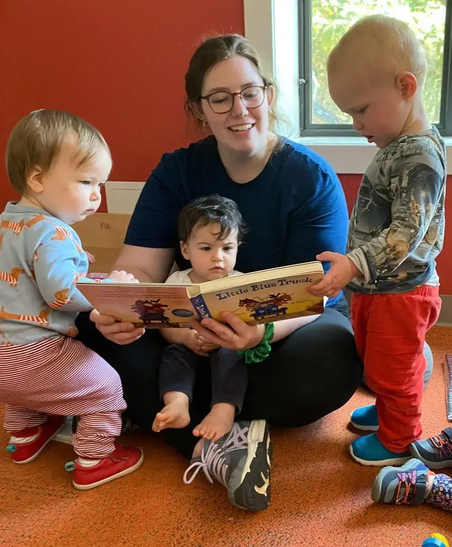 A teacher reading to toddlers in the Rainbow 1 classroom